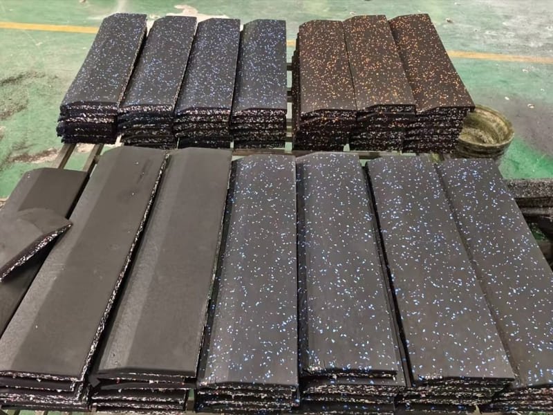 Un'inquadratura dettagliata del pavimento di una palestra in gomma nera con un bilanciere appoggiato sopra.